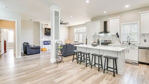 Une cuisine moderne dotée d’un îlot central, de tabourets de bar et d’un four encastré.