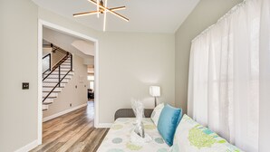 Un salon moderne avec un escalier en bois, un canapé agrémenté de coussins à motifs et une lampe blanche.