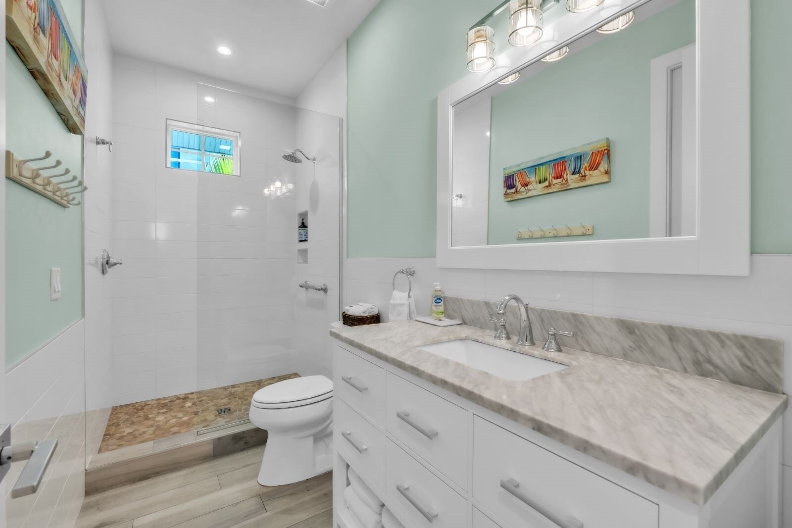 Un baño moderno con ducha, inodoro y tocador con lavabo y espejo.