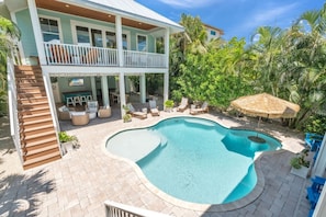 A two-story house with a swimming pool, outdoor furniture, and a covered patio area.