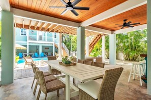 An outdoor patio with a pool, wicker furniture, and ceiling fans. - Jersey Girl 5 Bedroom Home by RedAwning (Anna Maria)