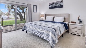 A bedroom with a bed, nightstands, a ceiling fan, and a view of the outdoors. - Adventure House Rryc17 2 Bedroom Condo by RedAwning (Rockport)