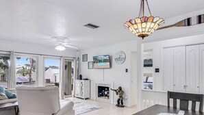A spacious living room with a large dining table, a fireplace, and a ceiling fan. - Adventure House Rryc17 2 Bedroom Condo by RedAwning (Rockport)