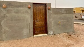 Een betonnen muur met een houten deur en decoratieve terracotta potten.
