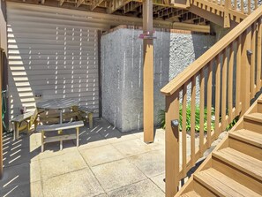 A wooden deck with a table and chairs, a concrete wall, and a staircase.