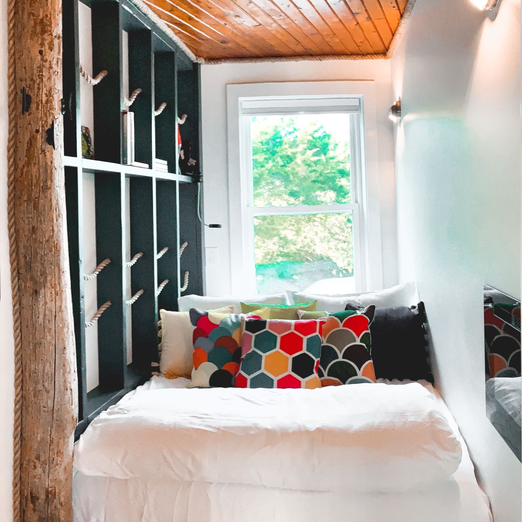 A bedroom with a bed, a window, and a built-in bookshelf.