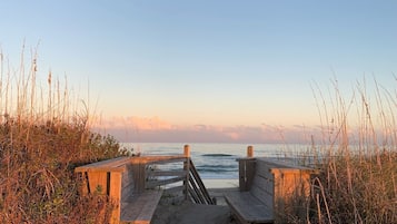 A wooden pathway leading to a beach with a wooden fence on either side.
