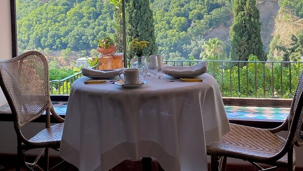 Mesa para dos con vistas a un castillo histórico y abundante vegetación.
