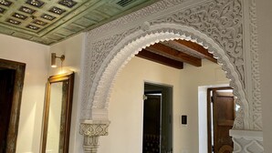 Un pasillo ornamentado con un arco decorativo, un espejo y una puerta.