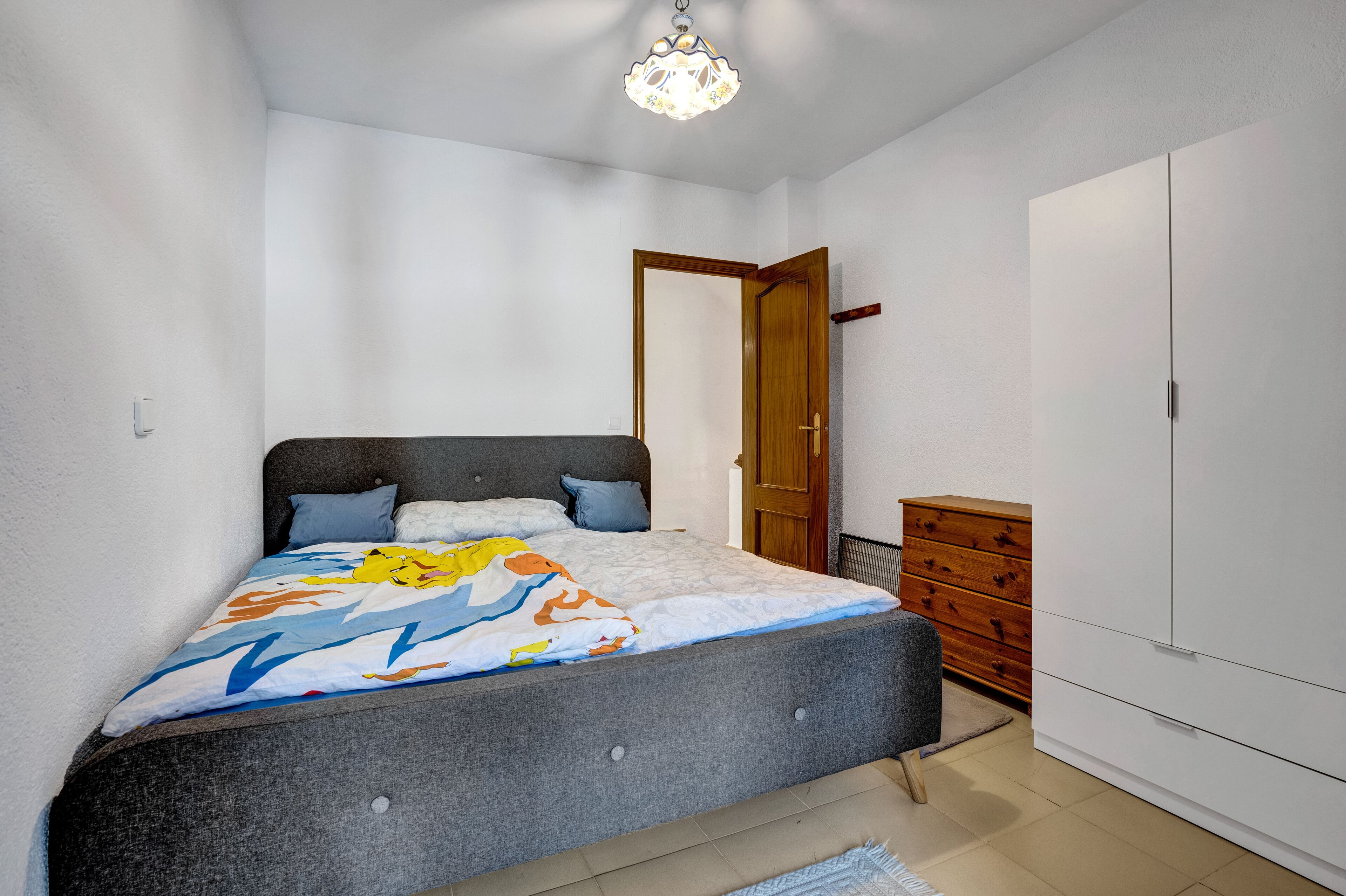 Une chambre à coucher avec un lit, une commode et une armoire.