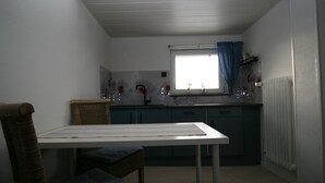 A compact kitchen with a window, a table, and a chair. - Ferienwohnung in Höhenlage mit Traumausblick (Sankt Oswald-Riedlhütte)