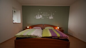 A single bed with a wooden headboard in a room with a green wall. - Ferienwohnung in Höhenlage mit Traumausblick (Sankt Oswald-Riedlhütte)