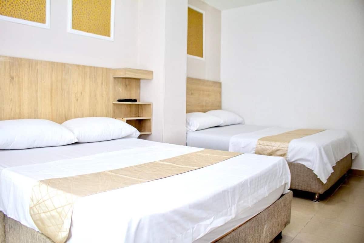Ein Hotelzimmer mit zwei Betten, Holz-Kopfteilen und einem kleinen Regal.