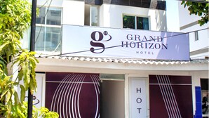The exterior of the Grand Horizon Hotel with a distinctive modern design, featuring a large sign with the hotel's name and logo.