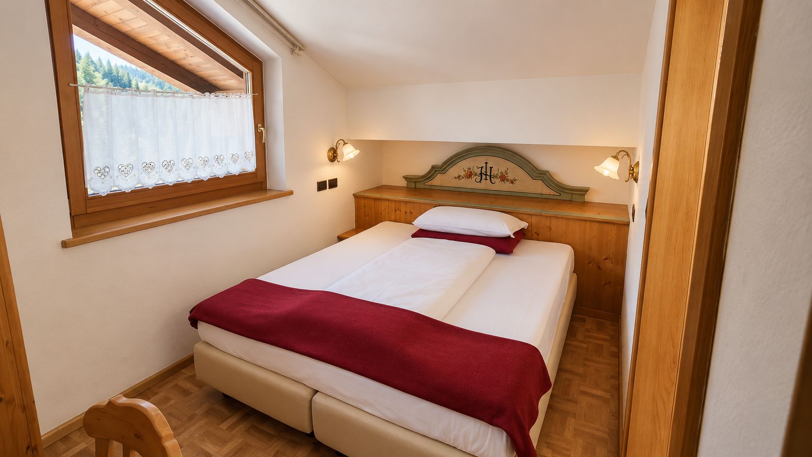 A bedroom with a bed, a wooden headboard, a window with a curtain, and a nightstand.