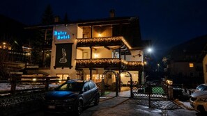 Een hotel met een naambord, een balkon met verlichting en een hekwerk.