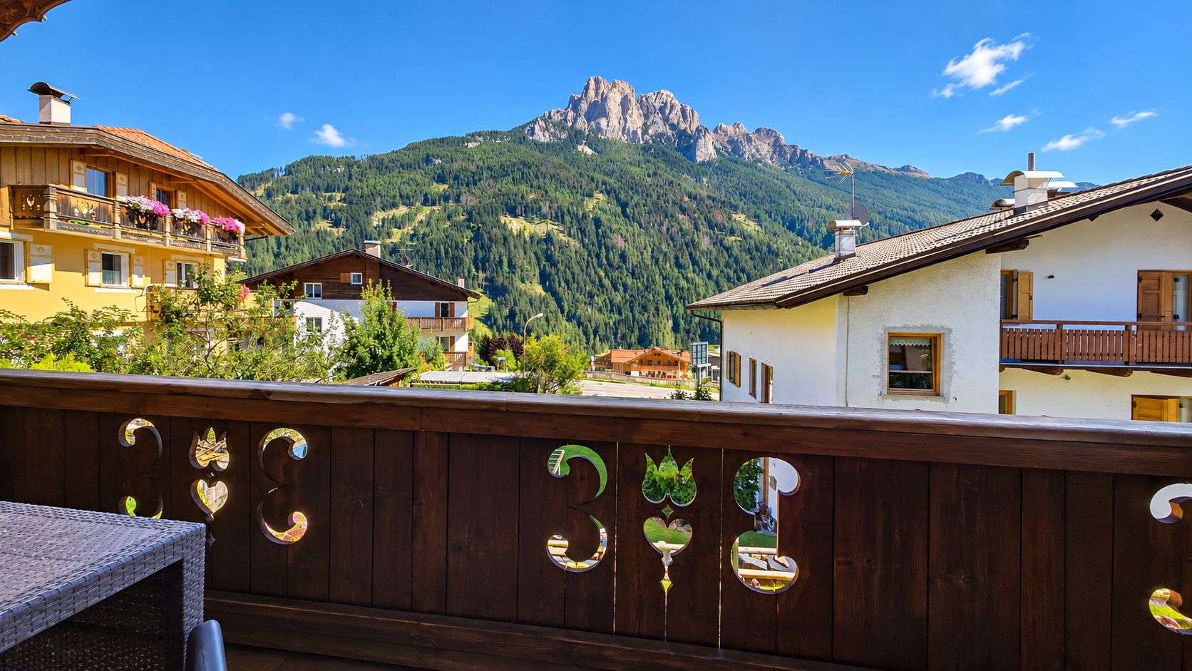 Un balcone in legno con vista su una montagna e diversi edifici.