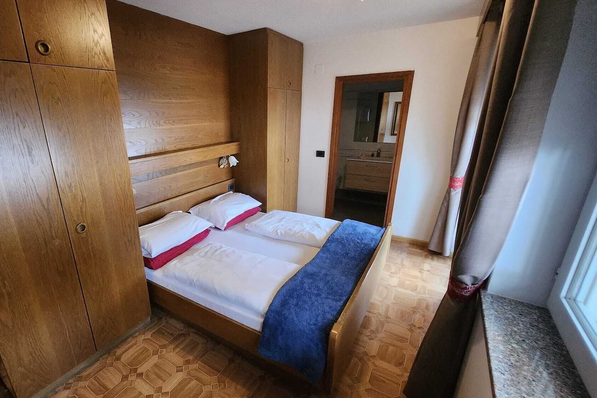 Ein Schlafzimmer mit einem Holzschrank, einem Bett mit weißer Bettwäsche und einer blauen Decke.