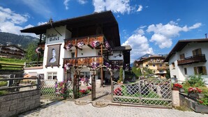 Un hotel alpino tradicional con balcón de madera, entrada decorada con flores y un letrero que dice "Hotel".