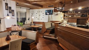 Un restaurante acogedor con muebles de madera, un televisor en la pared y un reloj.