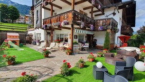 Un hotel con balcón decorado con flores, mobiliario exterior y una zona de juegos.