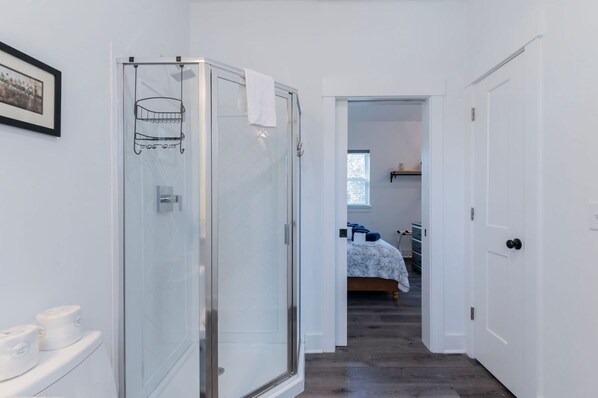 Ein schmaler Flur, der zu einem Schlafzimmer mit Bett und Fenster führt.