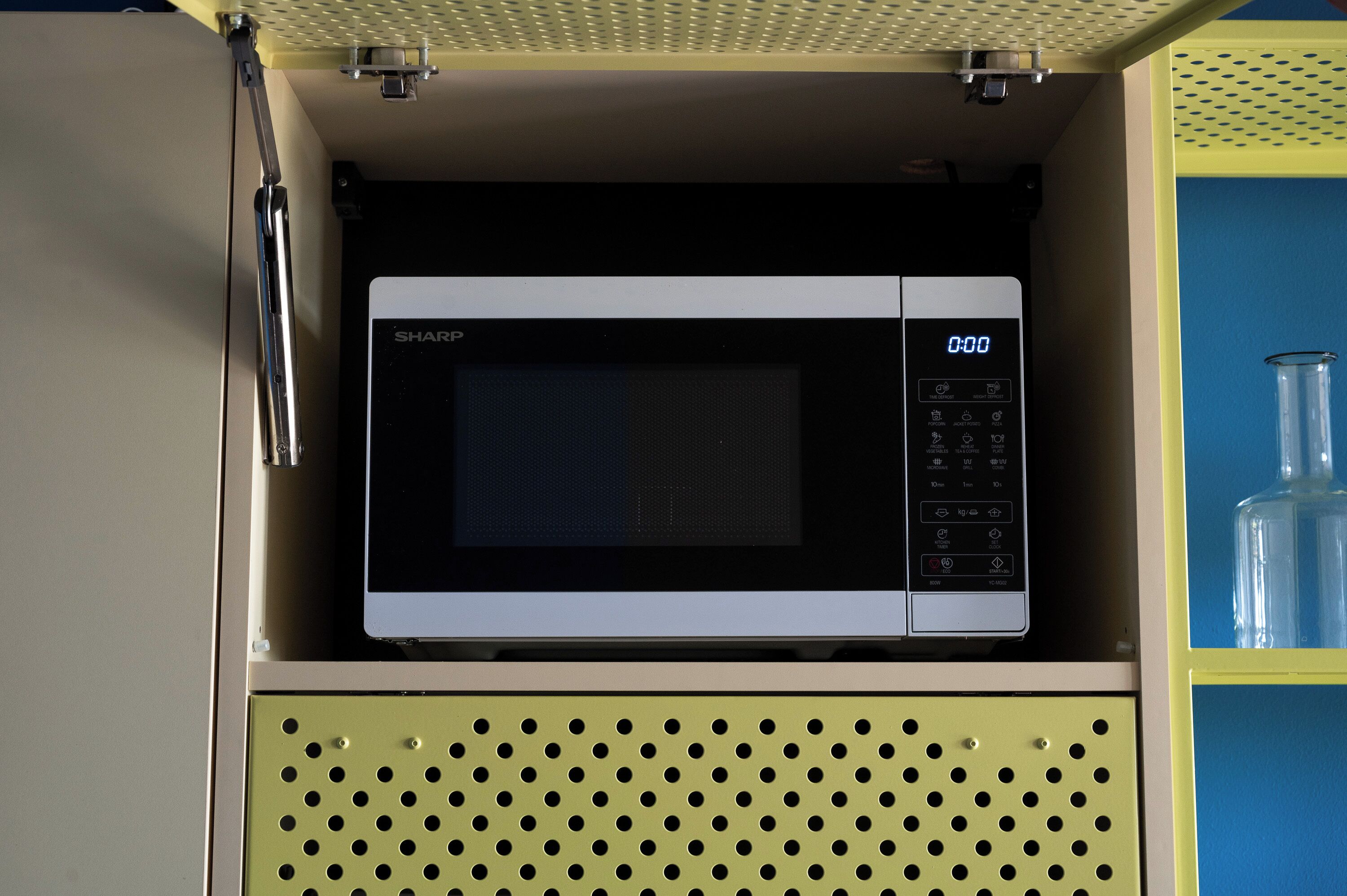 A microwave in a cabinet with a digital display.