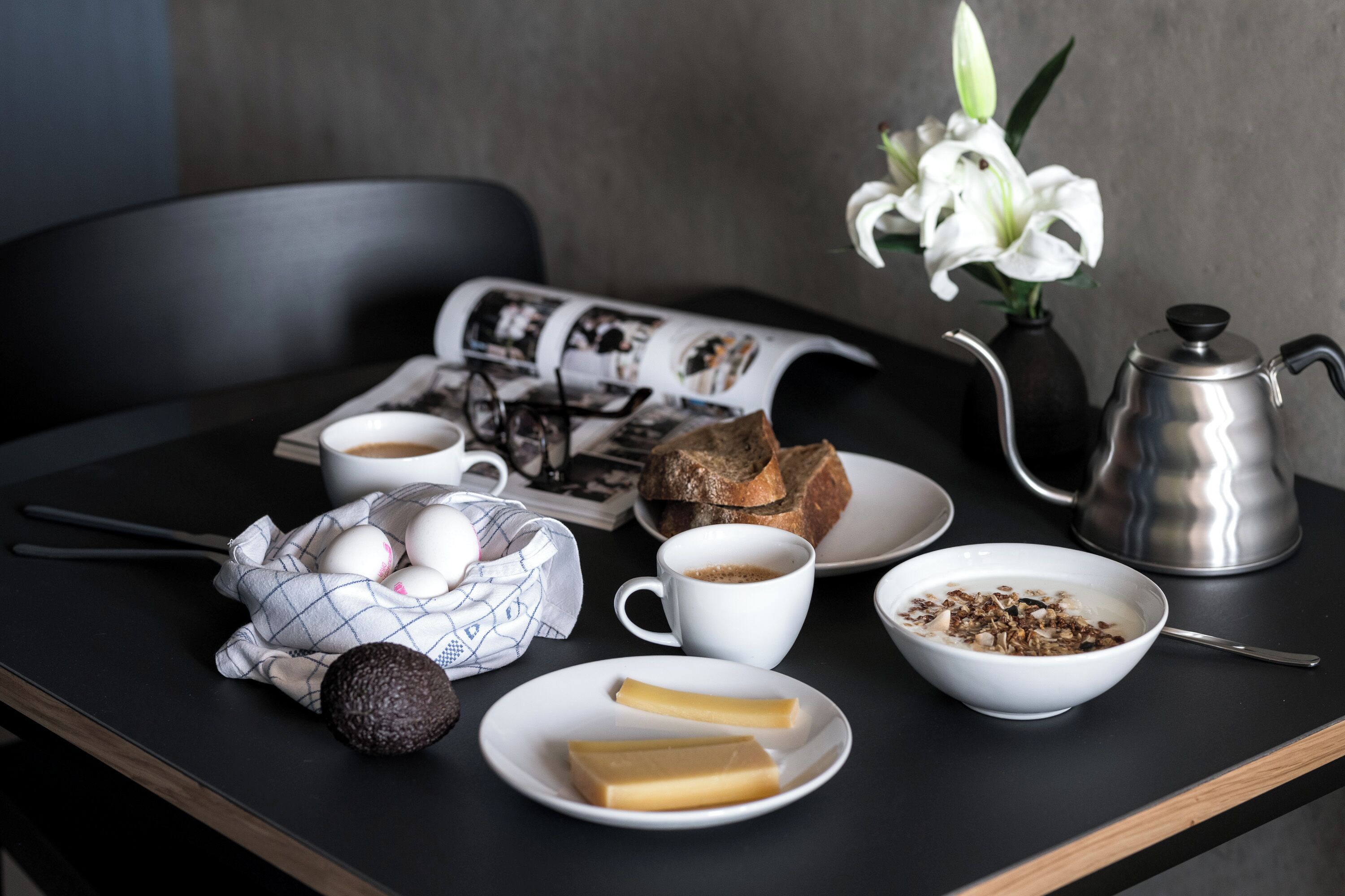 Ein Frühstückstisch mit Eiern, Brot, Kaffee und einer Zeitung.