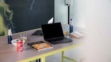 Una computadora portátil sobre una mesa con una revista, una cerveza y una botella de agua.