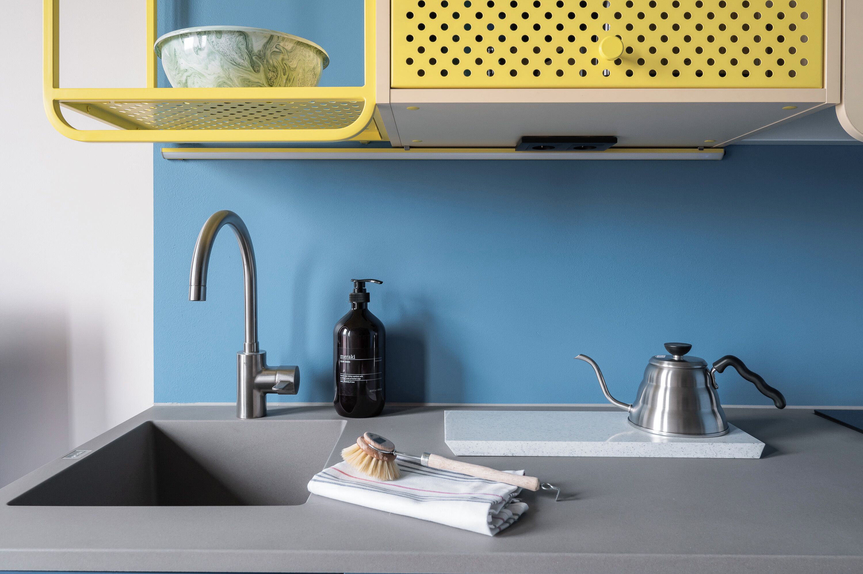 Una cocina moderna con un lavamanos, una cafetera y una botella de jabón.