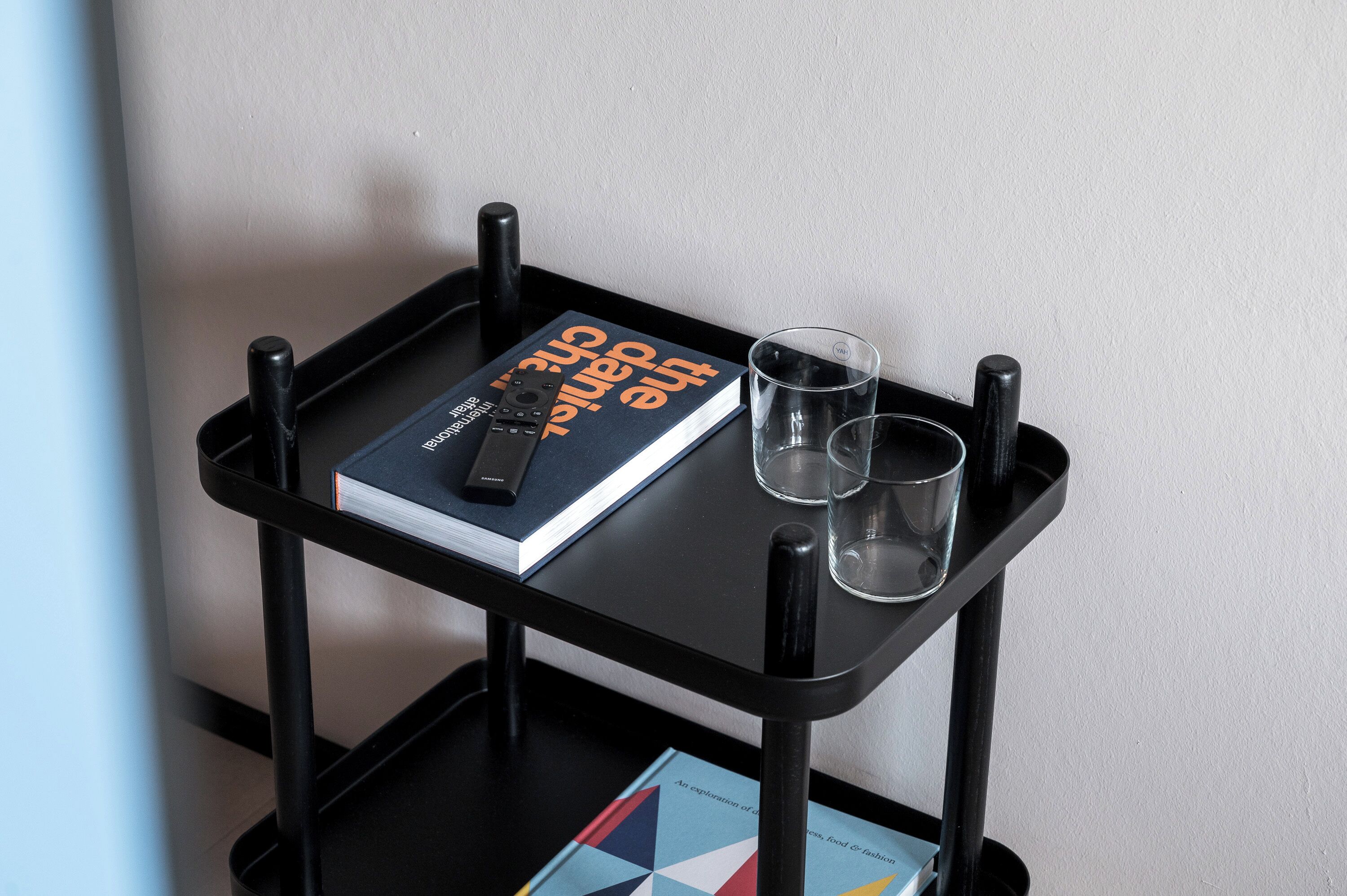 A black metal table with a book titled "The Art of Cooking" and two glasses.