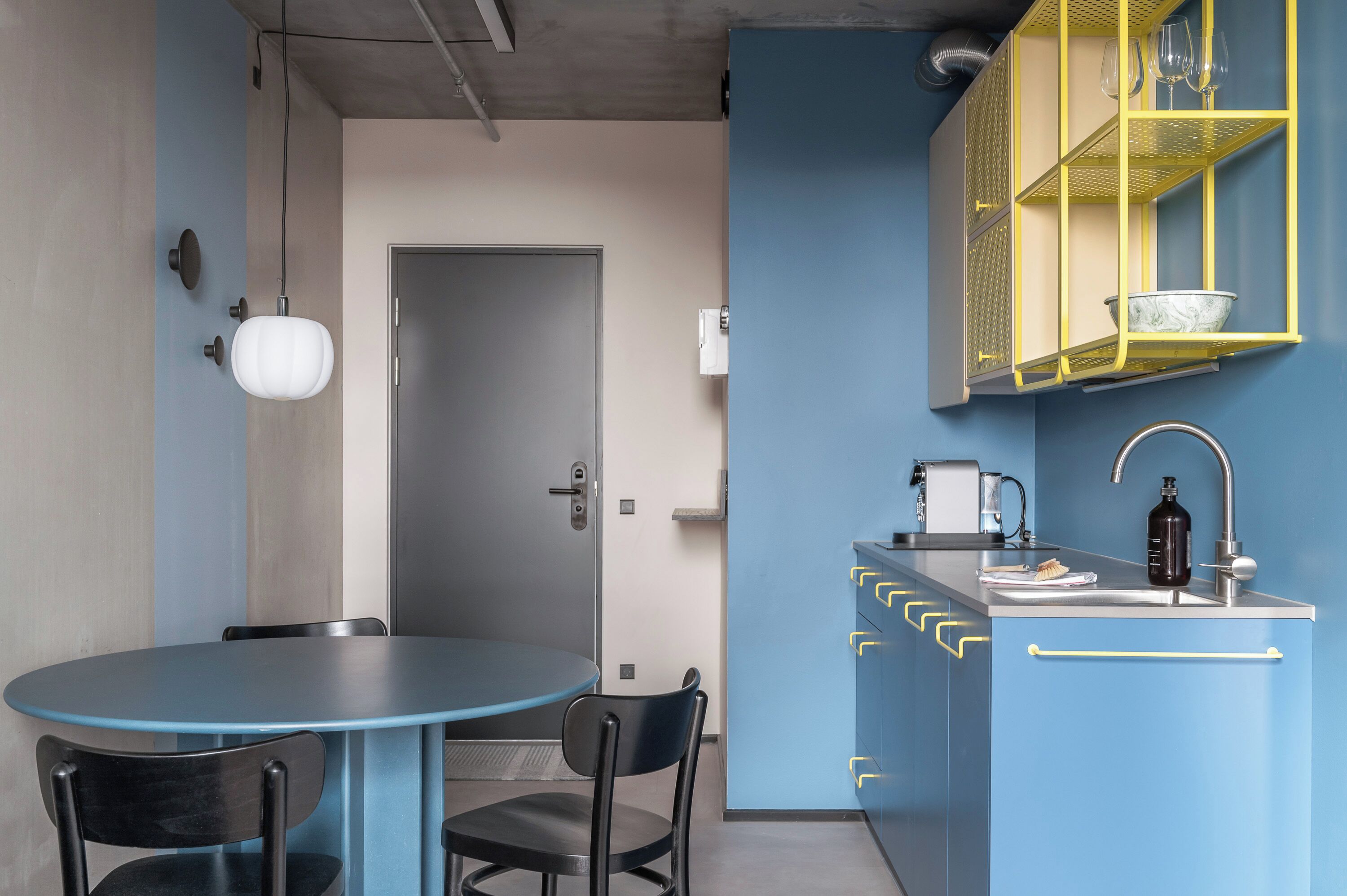A compact kitchen with a blue cabinet, a sink, and a small dining area with a table and chairs.