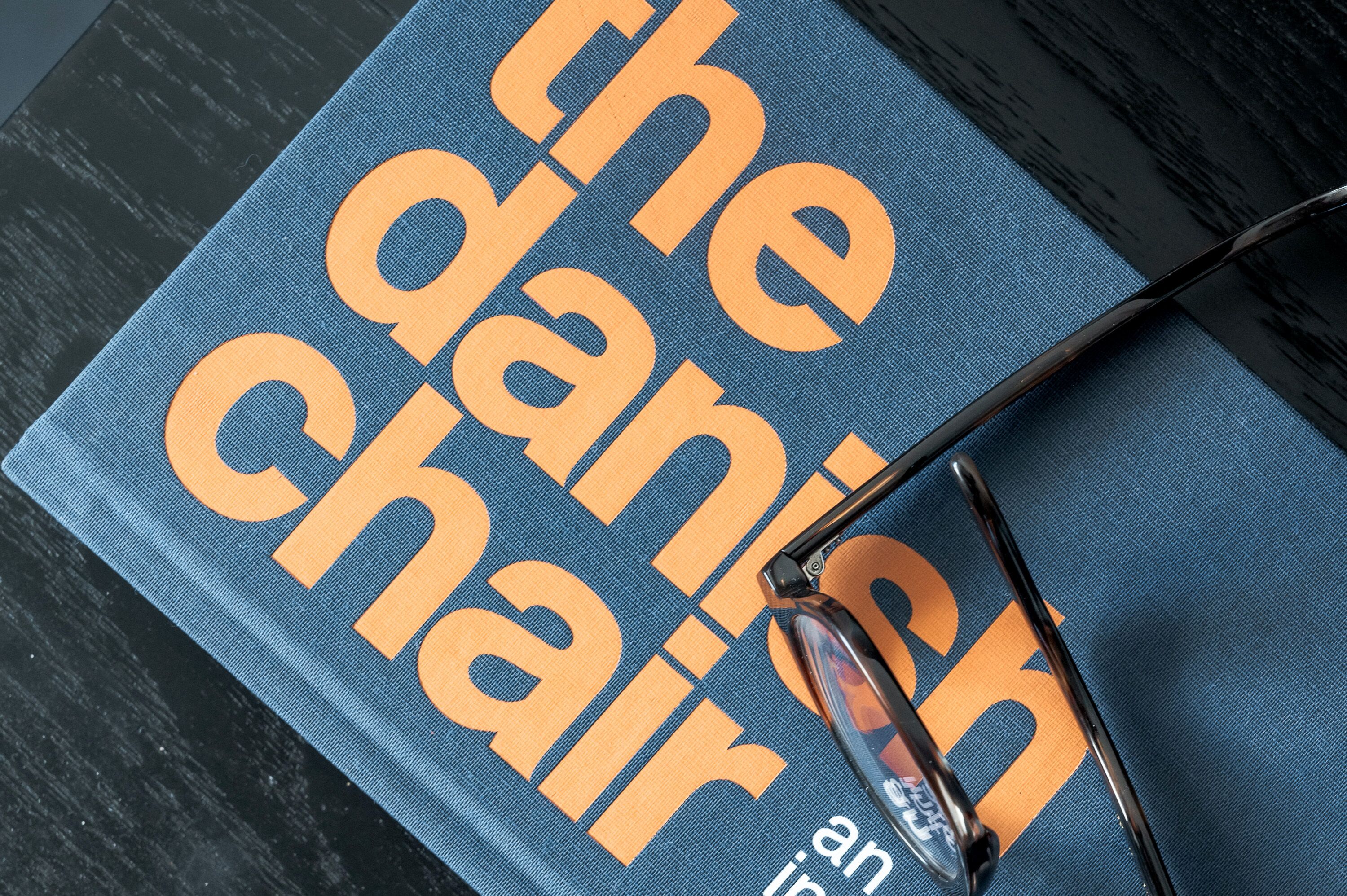 A blue book titled "The Danish Chair" with a pair of glasses on top.
