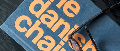 A blue book titled "The Danish Chair" with a pair of glasses on top.