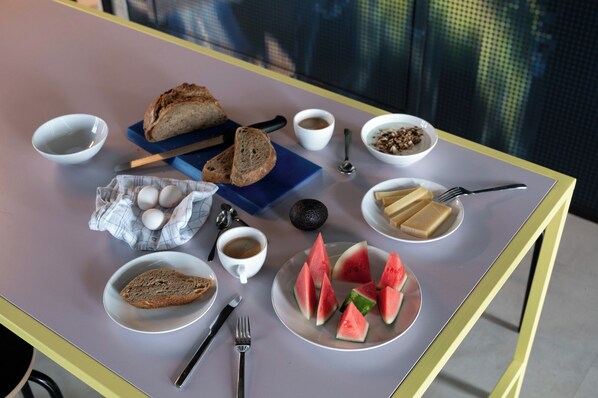 Una mesa de desayuno con pan, huevos, café y rebanadas de sandía.