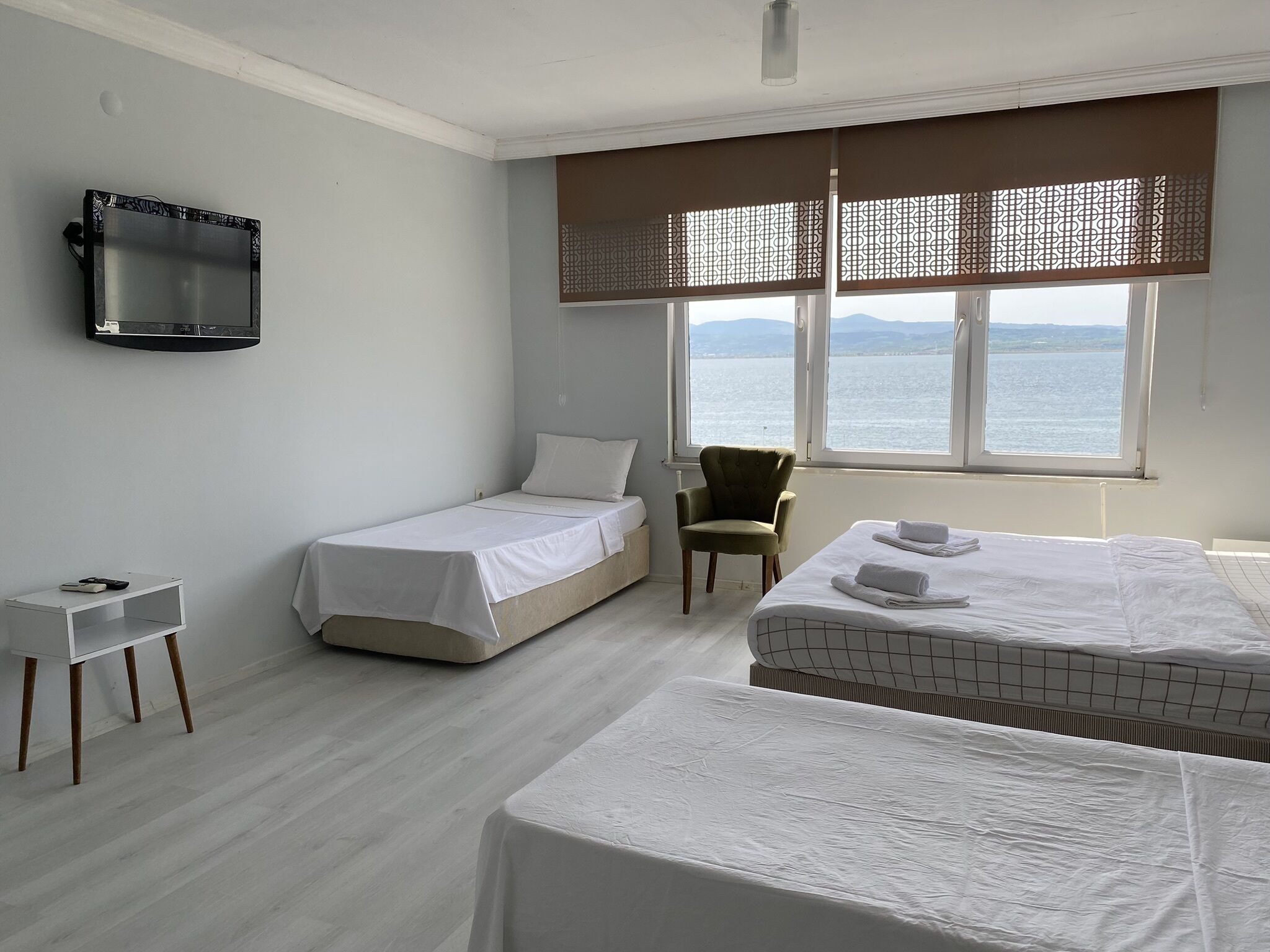 Ein Hotelzimmer mit zwei Betten, einem an der Wand befestigten Fernseher, einem kleinen Tisch und einem Sessel.