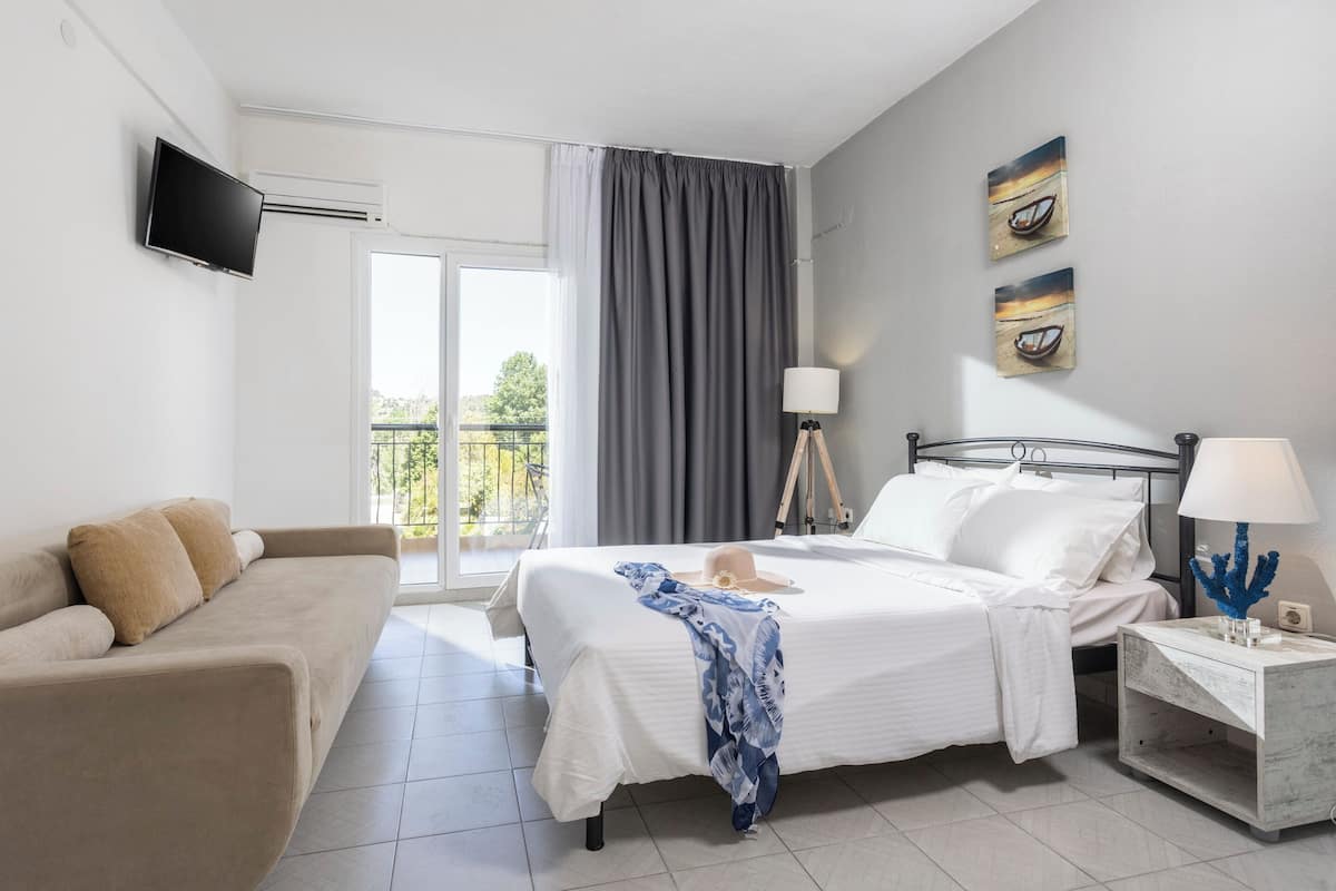 A bedroom with a bed, bedside tables, a TV, and a balcony view.