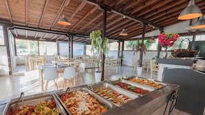 Un área de bufé con diversas opciones de comida, mesas y sillas de madera.