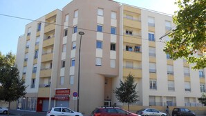 Un immeuble à plusieurs étages, avec une enseigne indiquant une boulangerie et un panneau interdisant le stationnement.