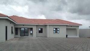 A modern building with a red-tiled roof, a paved driveway, and a garage.