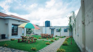 A courtyard with a picnic table, benches, and a colorful umbrella.