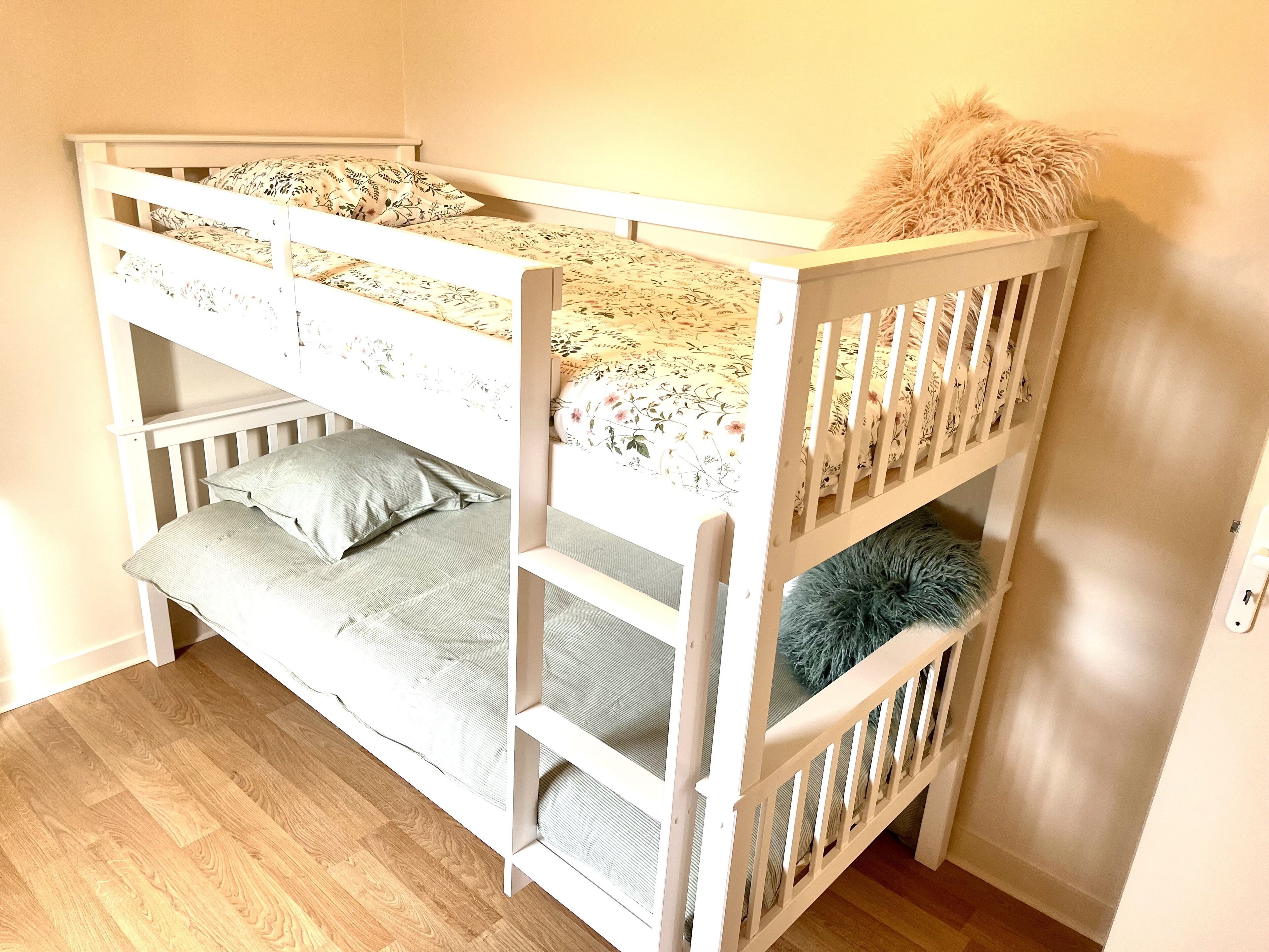 A bunk bed with floral bedding and a fluffy pillow.