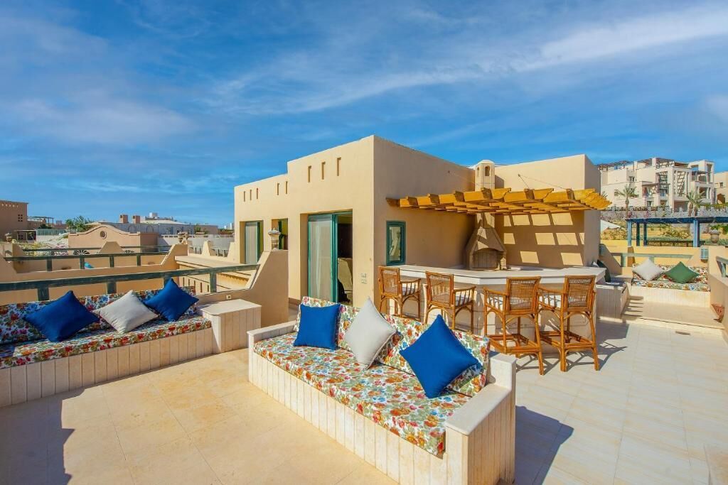 Una terrazza sul tetto con divanetti, un angolo bar e vista sugli edifici circostanti.