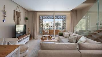 Una sala de estar moderna con sofá, televisor y comedor.