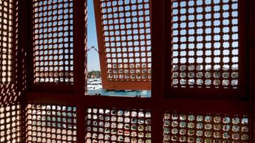 Una ventana con un diseño geométrico, a través de la cual se ve un puerto deportivo con barcos.