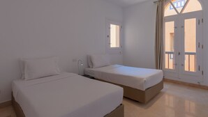 A room with two single beds, a window, and a door with a view. - Vesta - El Gouna Residence (El Gouna)