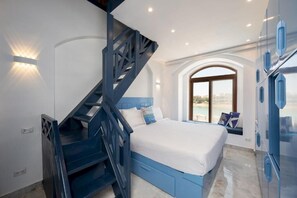 A bedroom with a bed, a staircase, a window with a view, and built-in cabinets.