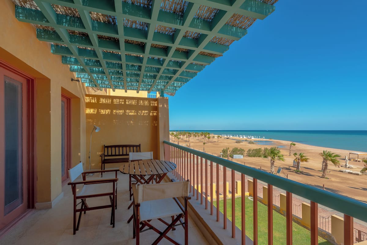 Ein Balkon mit Blick auf den Strand, einem Tisch und Stühlen sowie einer Pergola.