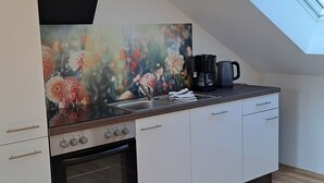 Eine moderne Küche mit Oberlichter, weißen Schränken, einem Herd und einer Kaffeemaschine.