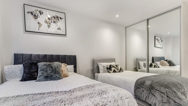 A modern bedroom with two beds, a large mirror, and a world map artwork. - 1 Bed, Sleeps 3, Free Parking, Wifi (Slough)